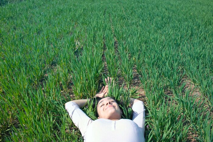 Woman with white t-shirt laying in a grass field 