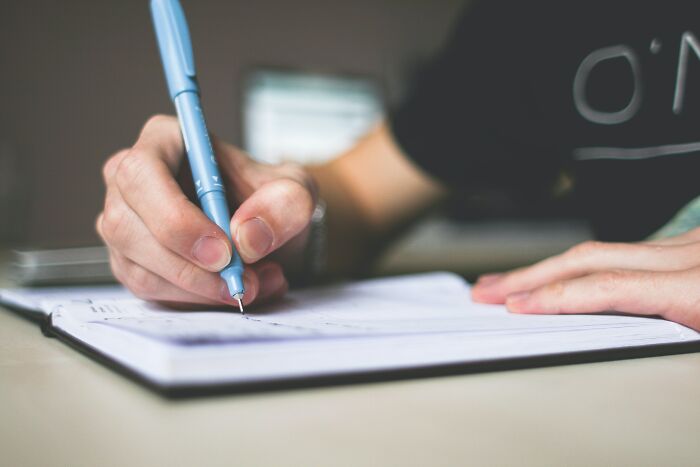 Person Writing A Letter In A Notebook 