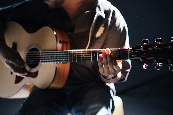 Person playing guitar for relaxing me time activity.