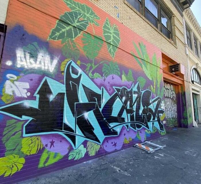 Colorful graffiti art on a city wall with vibrant leaves and abstract shapes, showcasing creative graffiti art.