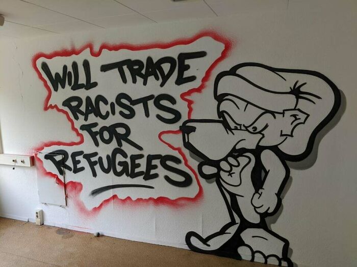 Graffiti art on a blank wall featuring a bold message and a cartoon character, showcasing creative graffiti art.