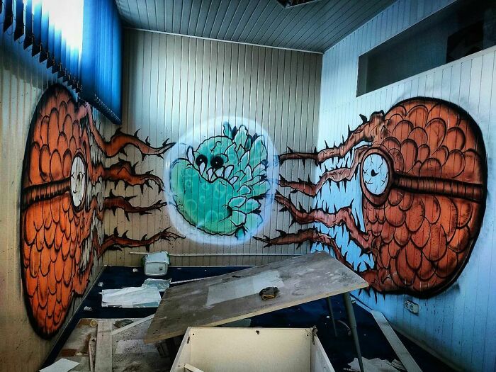 Graffiti art of a cracked orange sphere with a blue creature inside, transforming blank walls into creative urban art.