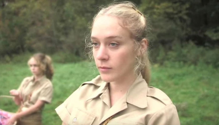 A scene with movie stars in a forest setting, wearing beige uniforms.