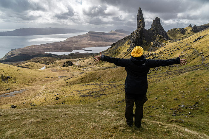 Traveler with arms outstretched overlooking rugged landscape, illustrating world travelers ranking friendliest nations.