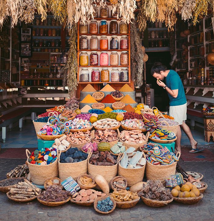Colorful spice market with baskets of herbs and goods, visited by a traveler exploring the friendliest nations worldwide.
