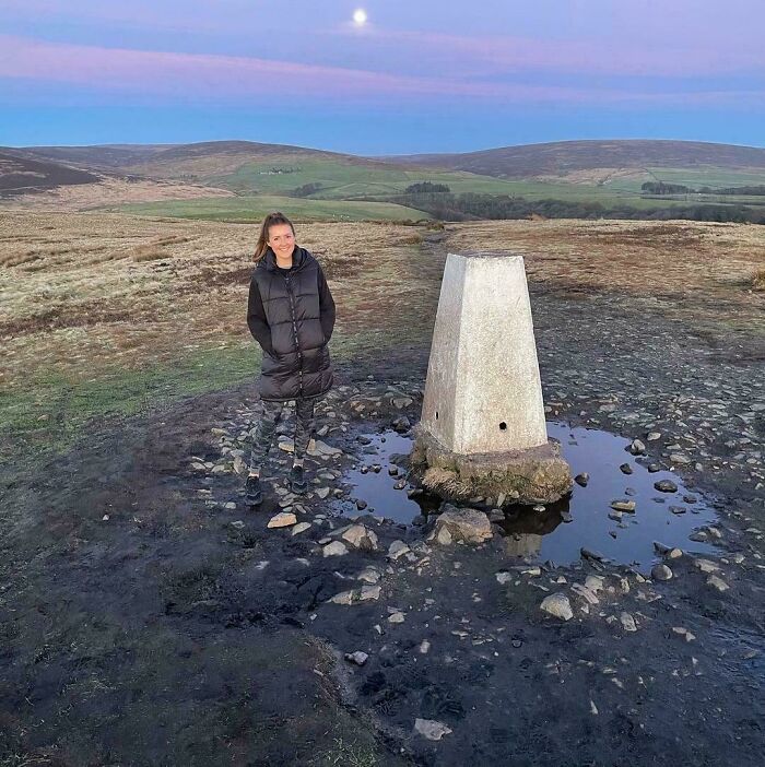 Woman in a field beside a concrete structure, with a mysterious reflection creating a confusing optical illusion.