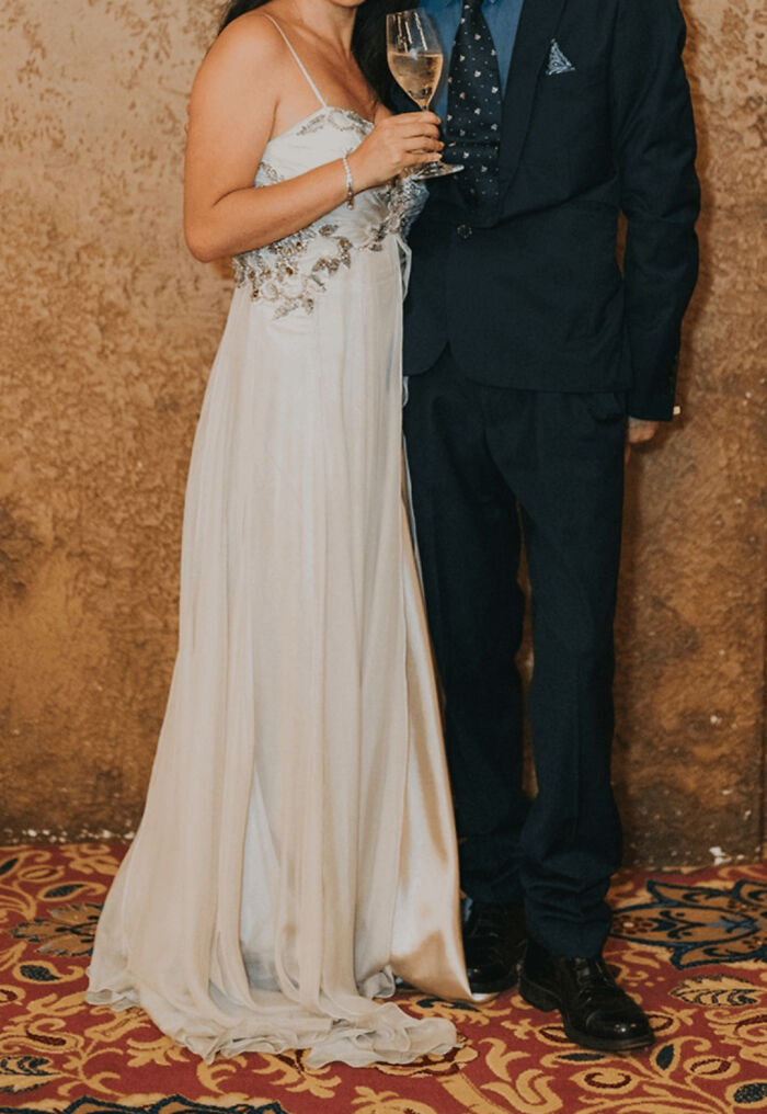 Couple at a wedding, woman in white dress holding a wine glass; a moment from unfortunate weddings shared online.
