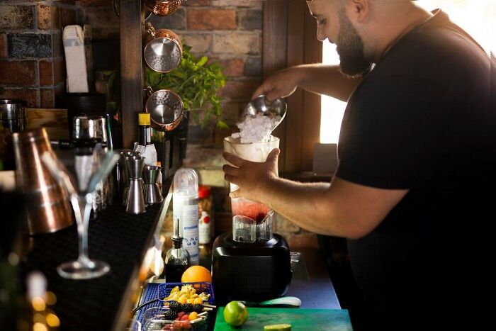 Bartender preparing a drink at the bar, surrounded by ingredients and equipment, highlighting unusual employee benefits.