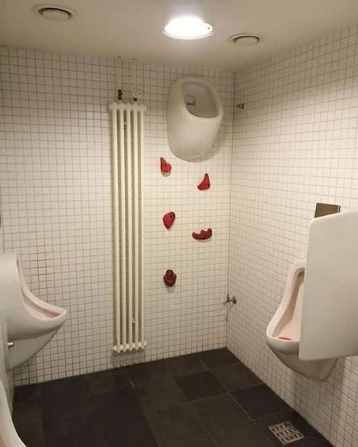 Unusual restroom with climbing holds on white tiled walls; a quirky cultureavenue feature.