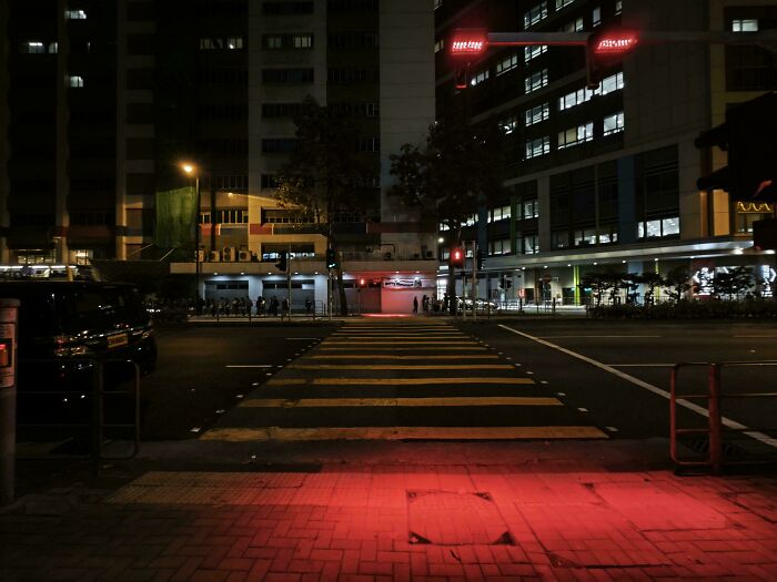 City street at night with empty crosswalk, showcasing tourist-interesting experiences in urban exploration.