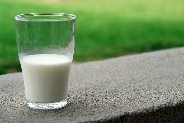 Glass of milk on a stone ledge with greenery in the background, related to hilarious overheard conversations.