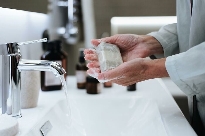 Hands washing with bar soap under a faucet, capturing a moment of hygiene.