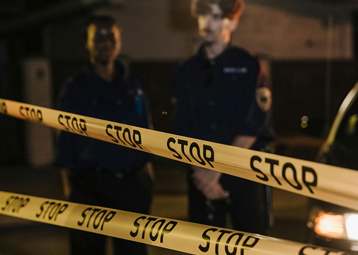 Police officers standing behind STOP tape, highlighting a scene where intuition to leave a situation is crucial.
