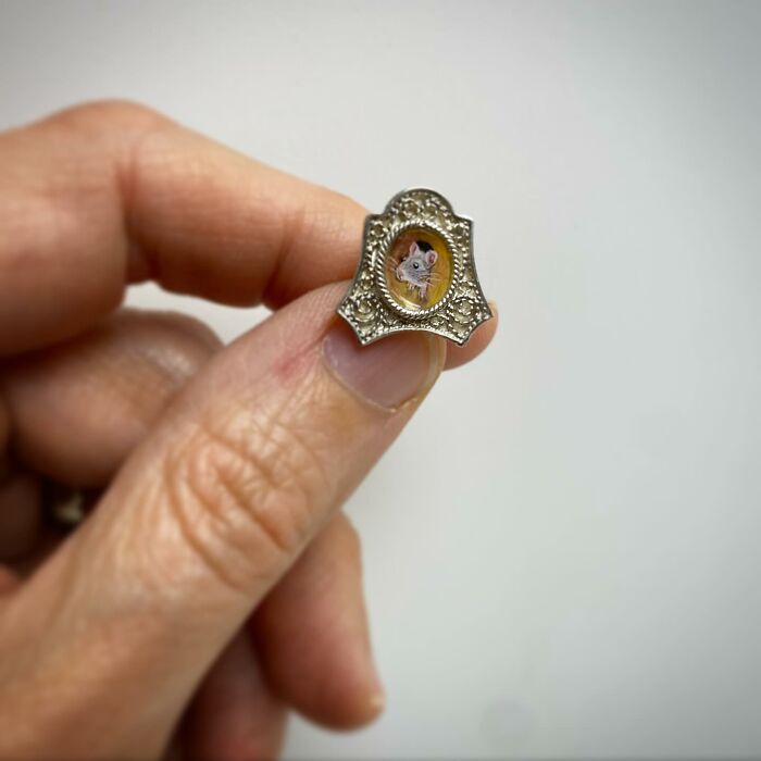 Hand holding a tiny one-inch painting of a mouse in an ornate frame by Brooke Rothshank.