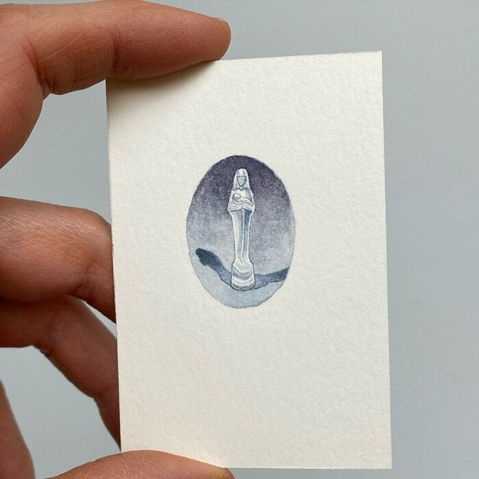 Hand holding a tiny one-inch painting of a chess piece resembling a queen in muted tones by Brooke Rothshank.