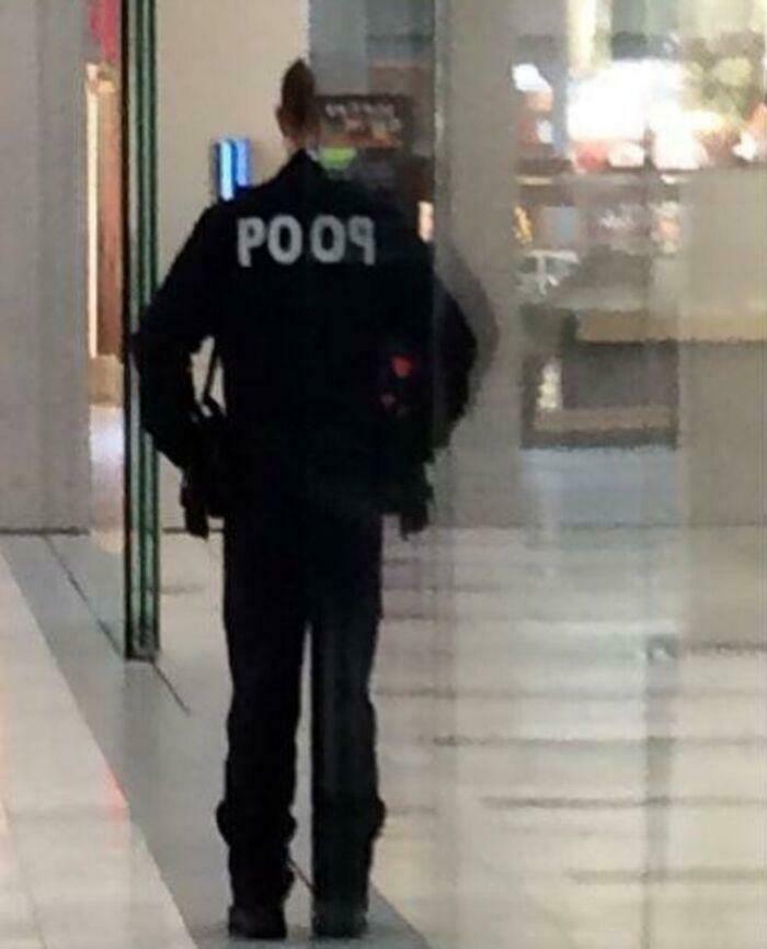 Blursed image of a person wearing a jacket with the word POO9 on the back, standing indoors in a hallway.