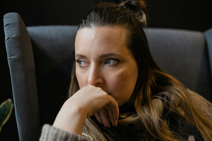 Woman looking concerned while sitting in a chair, symbolizing divorce papers served after caring for SIL’s kids.