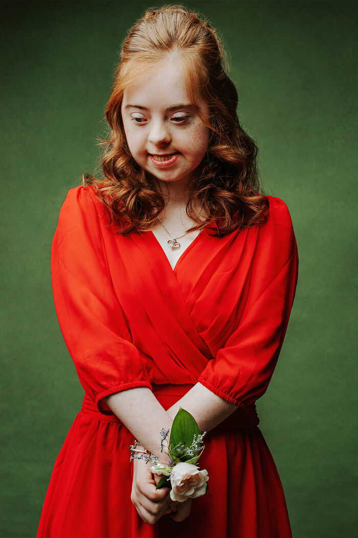 Young woman with Down syndrome in a red dress holding a flower, promoting inclusion and changing perceptions.