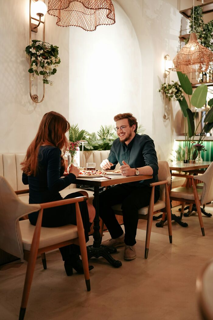 A man and woman enjoying a meal in a cozy restaurant, illustrating things men want women to know are a turn off.
