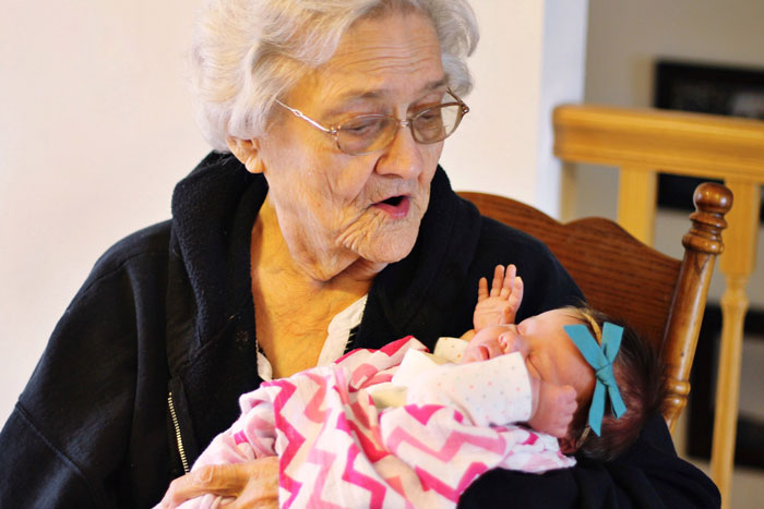 Elderly woman holding newborn baby wrapped in pink blanket, illustrating MIL steals baby and claims it’s a gift.