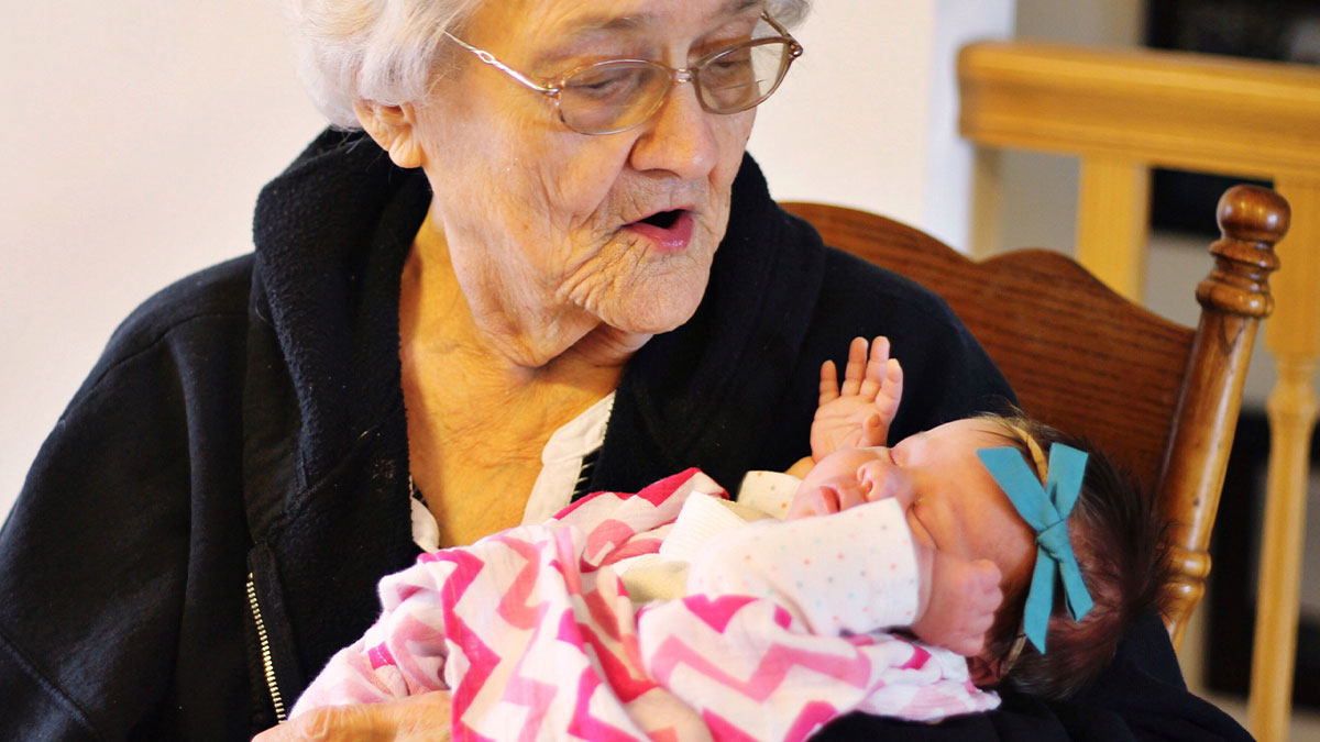 Elderly woman holding a baby wrapped in a pink blanket, illustrating a mother-in-law stealing baby story.