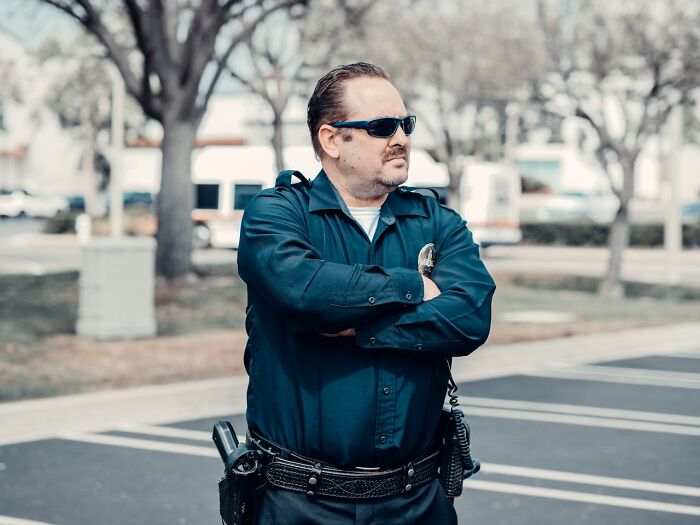 Security officer standing outside with arms crossed wearing sunglasses during daytime, illustrating reasons people called off their wedding.