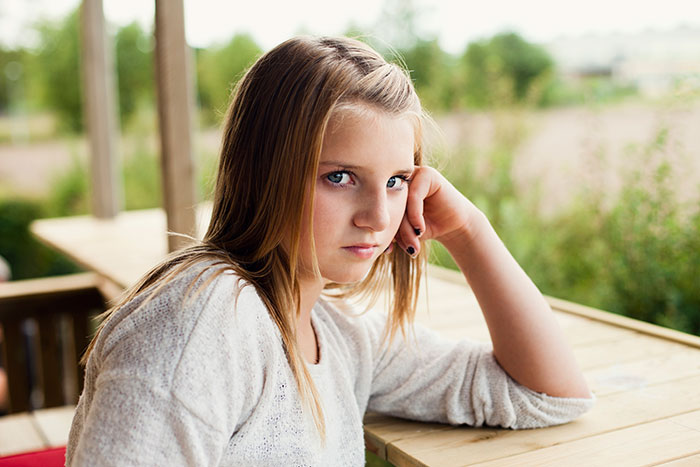 Teenage girl looking thoughtful outdoors, illustrating enforcing basic boundaries during daughter's sleepover.